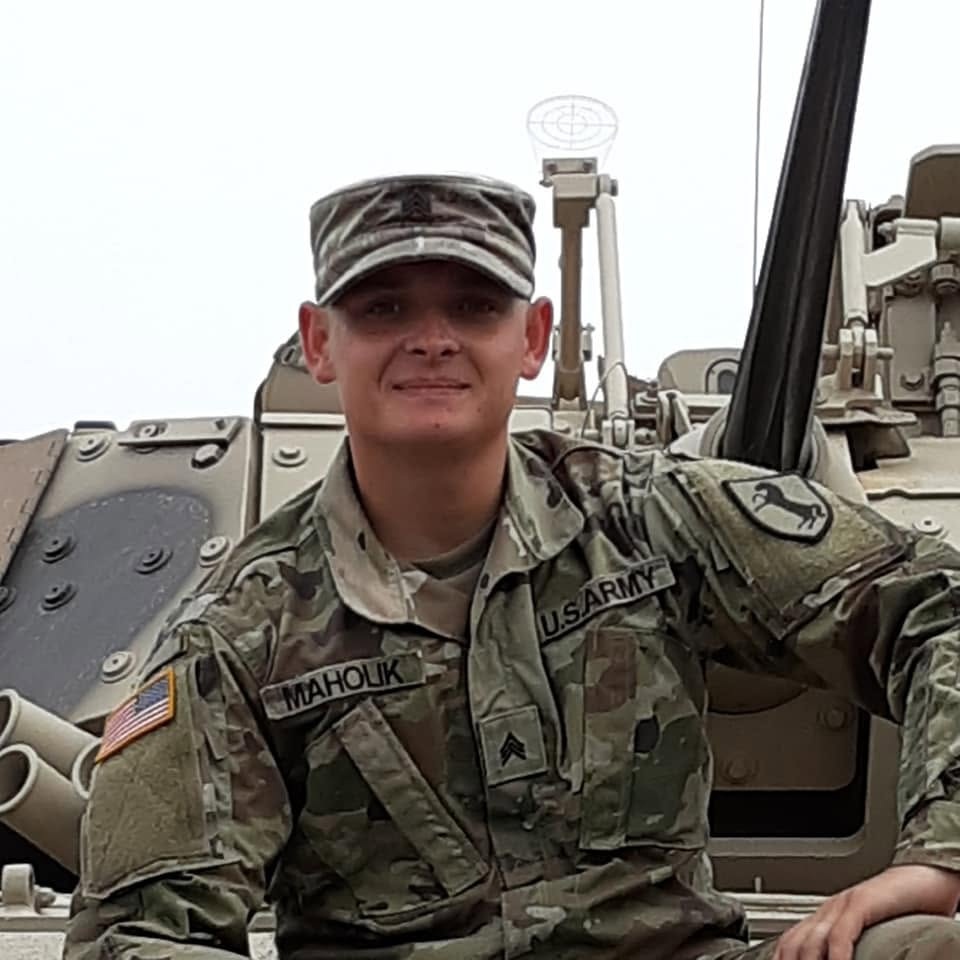 Robbie Jordan in his U.S. Army uniform beside a military vehicle