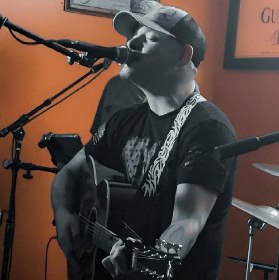 Robbie singing into a microphone with his guitar
