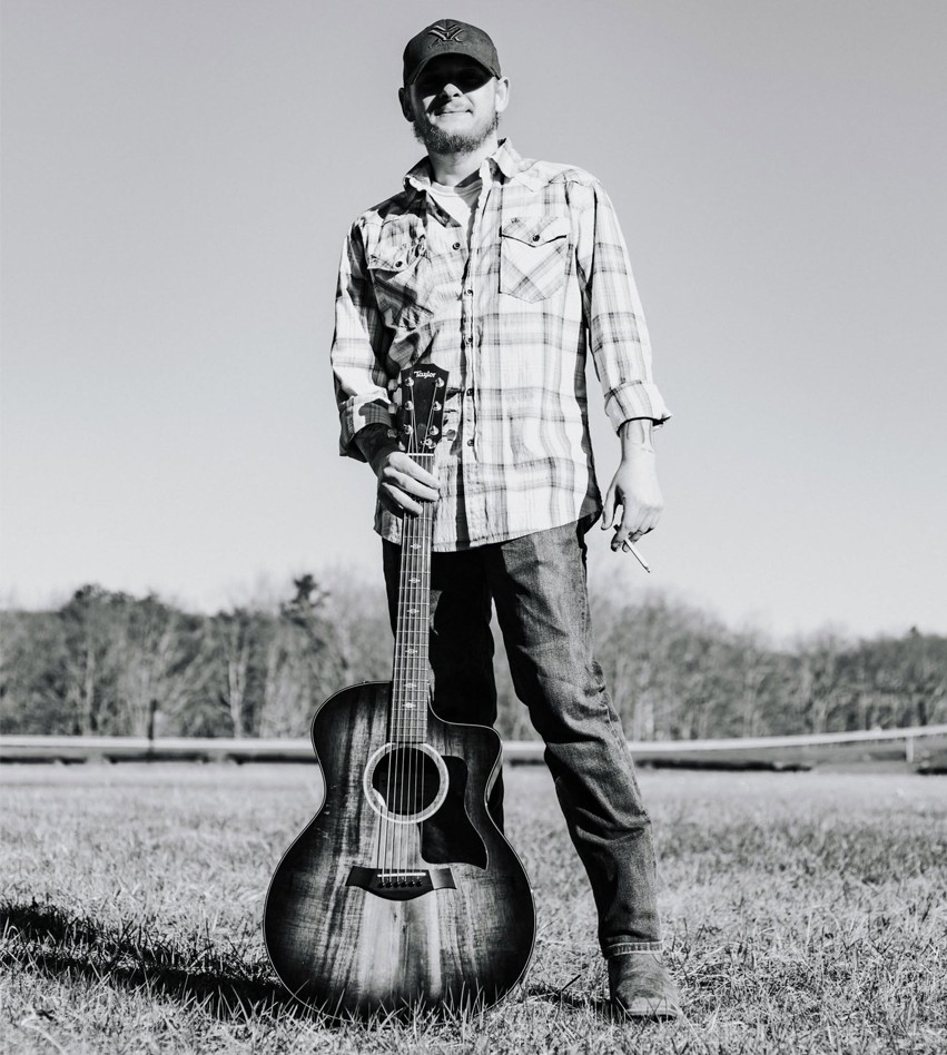 Robbie standing with an acoustic guitar